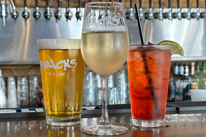 image of glass of beer, glass of wine, and a cocktail on a bar